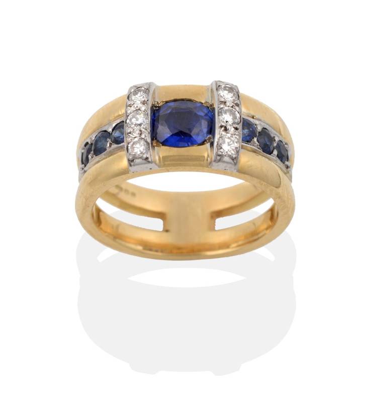 Lot 2128 - An 18 Carat Gold Contemporary Sapphire and Diamond Ring, an oval cut sapphire, within a trio of...