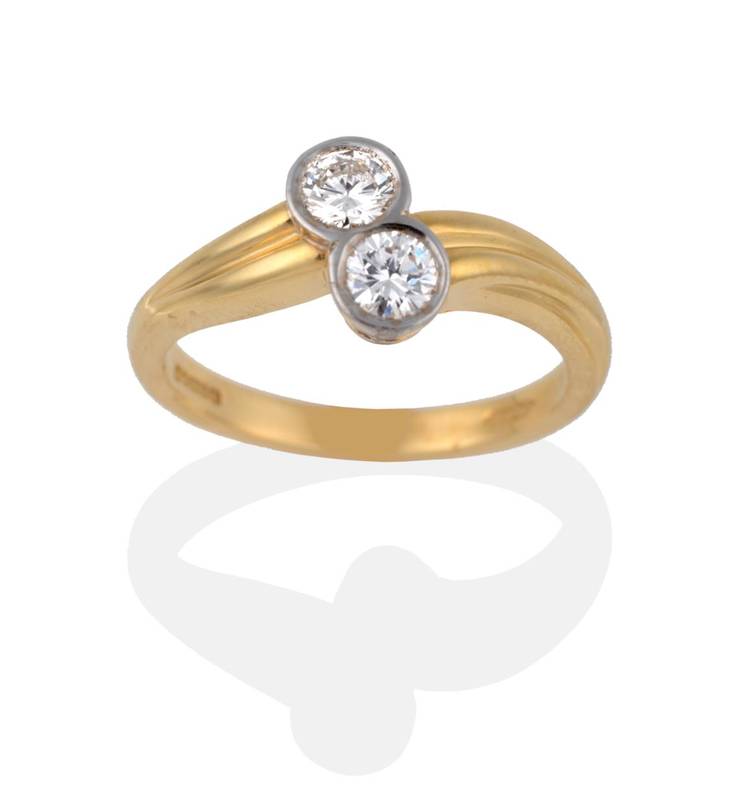 Lot 2143 - An 18 Carat Gold Diamond Two Stone Twist Ring, each round brilliant cut diamond in a white...