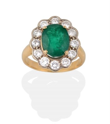 Lot 2147 - An Emerald and Diamond Cluster Ring, the oval mixed cut emerald within a yellow four claw...