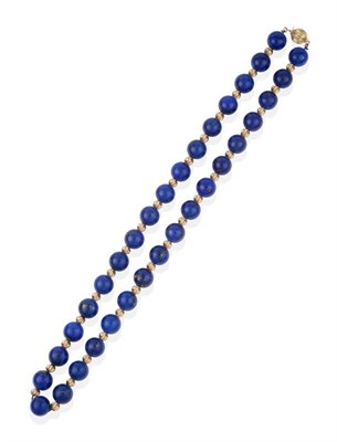 Lot 2151 - A Lapis Lazuli Bead Necklace, lapis lazuli beads alternating with fluted spacer beads, to a...