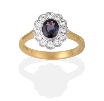 Lot 2156 - An 18 Carat Gold Colour-Change Sapphire and Diamond Cluster Ring, the oval mixed cut sapphire...