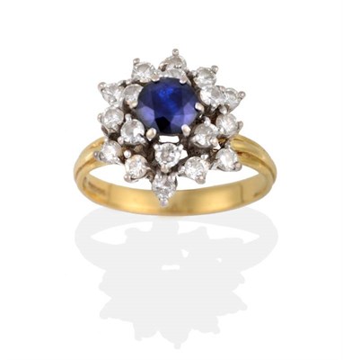 Lot 2162 - An 18 Carat Gold Sapphire and Diamond Cluster Ring, a round cut sapphire above spaced rows of round