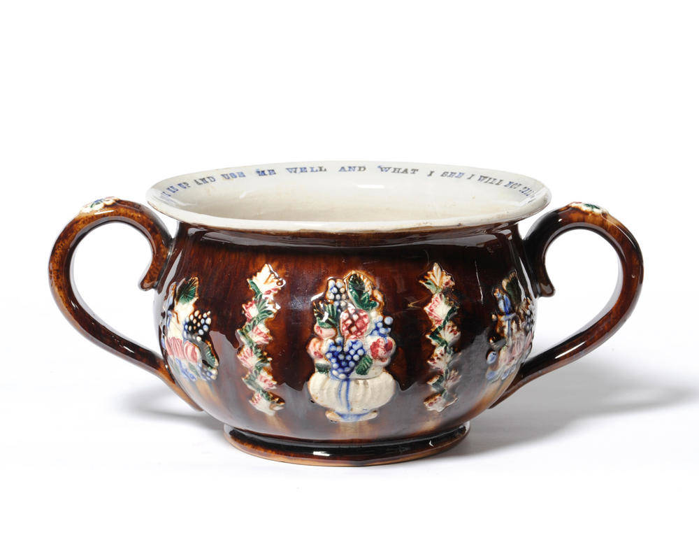 Lot 104 - A Measham Bargeware Twin-Handled Chamber Pot, 1882, applied with foliage on a treacle ground,...