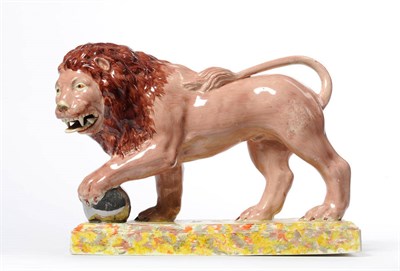 Lot 111 - A Staffordshire Pottery Figure of a Lion, circa 1820, the beast depicted with a paw raised on a...