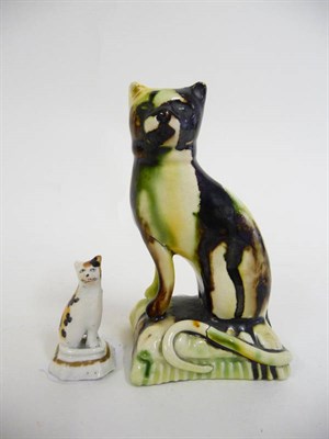 Lot 151 - A Cream Coloured Earthenware Cat, 19th century, sitting on a cushion moulded base decorated in...