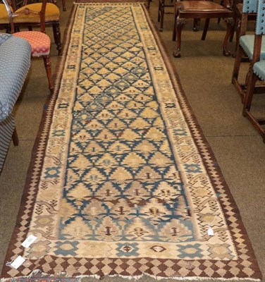 Lot 1252 - Iranian tribal Kilim runner, the mid indigo field of stylised planted enclosed by ivory...