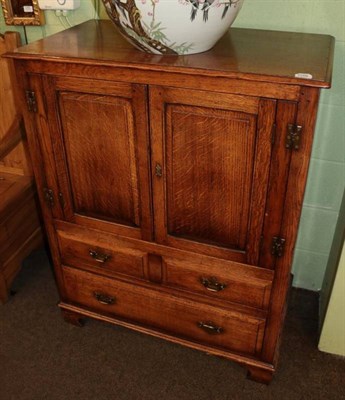 Lot 1268 - A reproduction oak cupboard, with moulded cupboard doors above two short and one long drawer,...