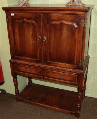 Lot 1272 - An oak cupboard, modern, with moulded doors enclosing a divided shelf, two frieze drawers below, on