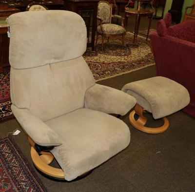 Lot 1330 - An Ekornes revolving and reclining armchair, modern, upholstered in beige velvet, with beech frame