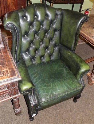 Lot 1345 - A Georgian style buttoned green leather wing back armchair