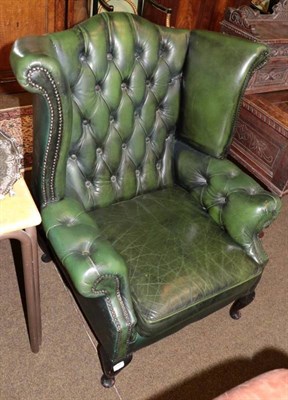 Lot 1346 - A Georgian style buttoned green leather wing back armchair