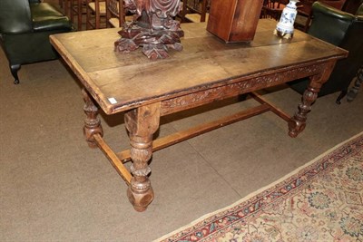 Lot 1386 - A carved oak dining table, the three-plank top with cleated ends above a carved frieze of...