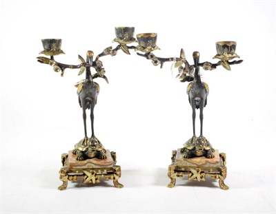 Lot 238 - A pair of Japanese parcel gilt bronze twin branch candlesticks, Meiji period, the supports modelled