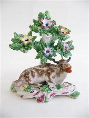 Lot 201 - A Bow Figure of a Recumbent Cow, circa 1770, on scroll moulded base, floral bocage, picked out...