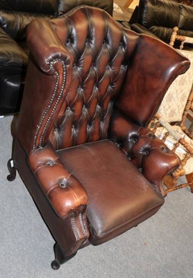 Lot 1253 - A George III style brown leather buttoned wing chair