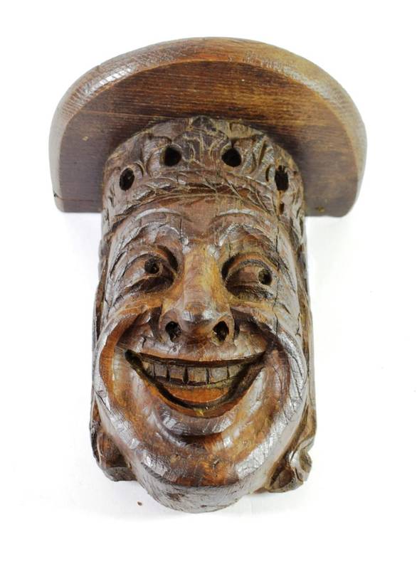 Lot 104 - A Carved Oak Bracket, in 16th century style, as a crowned smiling head, 25cm high; with later shelf