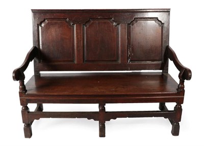 Lot 339 - A Late George III Joined Oak Settle, early 19th century, the back support with three fielded panels