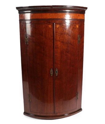 Lot 442 - A George III Mahogany and Satinwood Banded Bowfront Hanging Corner Cupboard, late 18th century, the