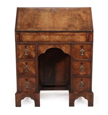 Lot 493 - A Walnut and Featherbanded Kneehole Desk, the crossbanded top above a fall enclosing a fitted...