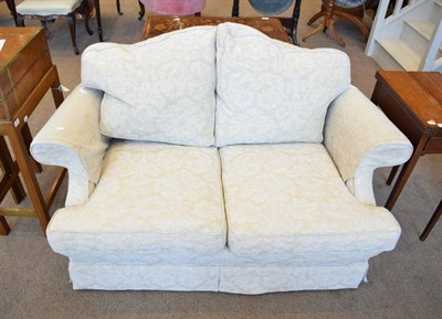 Lot 573 - ~ A Feather Filled Two-Seater Sofa, modern, covered in beige and cream fabric, with scrolled...