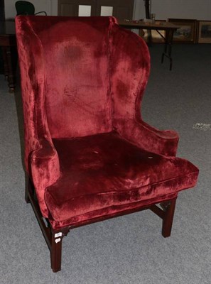 Lot 583 - A George III Style Wing-Back Armchair, early 20th century, covered in red velvet with outswept arms