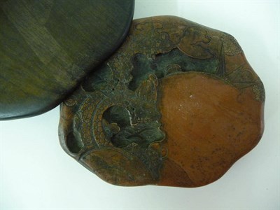 Lot 320 - A Chinese Red Inkstone, 19th century, of shaped oval form, carved with a bird in a tree and...