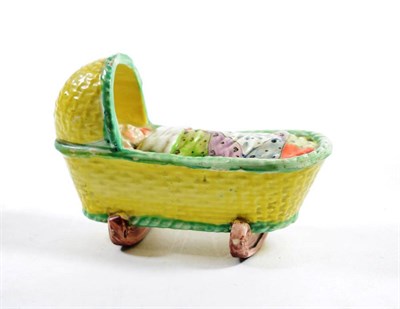 Lot 1317 - A Pearlware Cradle Group, circa 1800, modelled as a young child in a basket moulded crib, 12cm...