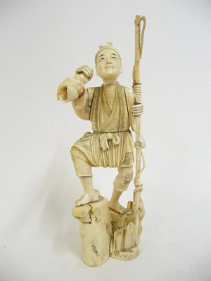 Lot 345 - A Japanese Sectional Ivory Okimono, Meiji Period (1868-1912), of a man holding a roped staff in one