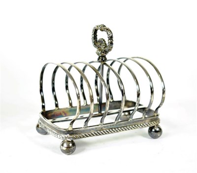 Lot 1663 - A George V Silver Toast Rack, George Howson, London 1910, with central foliate handle, gadroon...