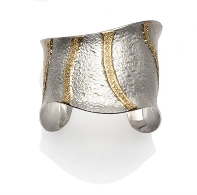 Lot 373 - A Contemporary Silver Bangle, the hammered surface with four lines of gold overlay, two set...