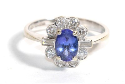 Lot 97 - An 18 carat white gold tanzanite and diamond cluster ring, the oval cut tanzanite in four...