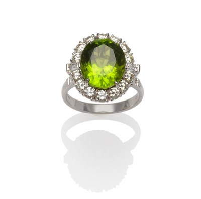 Lot 408 - An 18 Carat White Gold Peridot and Diamond Cluster Ring, the oval cut peridot within a border...