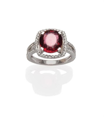 Lot 411 - A Garnet and Diamond Ring, an oval cut garnet within a border of round brilliant cut diamonds...