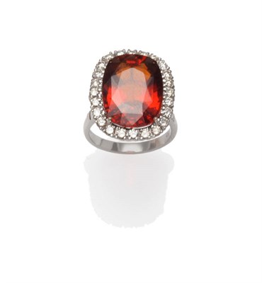 Lot 413 - A 18 Carat White Gold Garnet and Diamond Cluster Ring, an oval mixed cut garnet within a border...