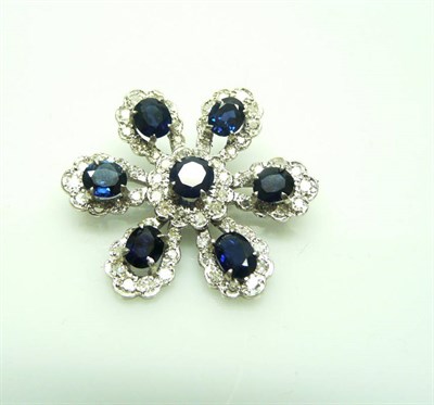 Lot 419 - A Sapphire and Diamond Brooch, as a stylised flower, each petal set with a sapphire within a border