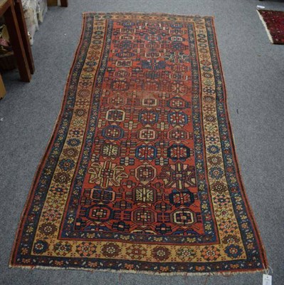 Lot 1235 - An Indo-Persian rug, the central brick-red field with three columns of geometric medallions, within