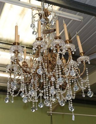 Lot 1476 - A gilt metal and cut glass twelve-light chandelier, the scroll branches with urn sconces and...