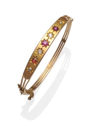 Lot 463 - A 9 Carat Gold Ruby and Diamond Hinged Bangle, graduated old cut diamonds and oval cut rubies...