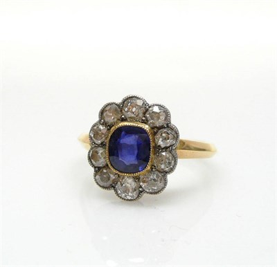 Lot 471 - A Sapphire and Diamond Cluster Ring, the central mixed cut sapphire in a yellow millegrain...