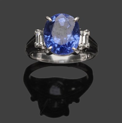 Lot 479 - A Sapphire and Diamond Ring, the oval mixed cut sapphire in a white four claw setting is flanked by
