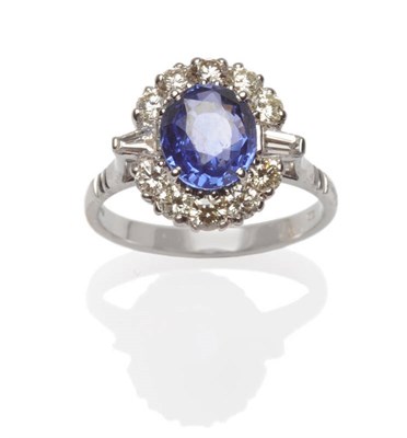 Lot 505 - An 18 Carat White Gold Sapphire and Diamond Cluster Ring, an oval mixed cut sapphire within a...