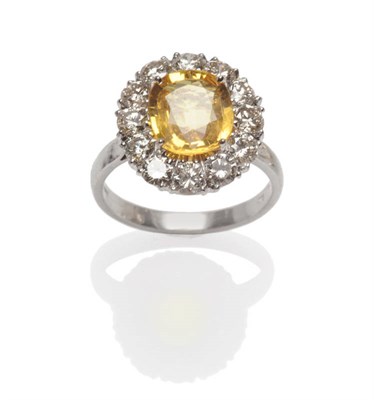 Lot 506 - An 18 Carat White Gold Yellow Sapphire and Diamond Cluster Ring, the oval cut yellow sapphire...