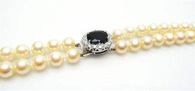 Lot 511 - A Two Row Cultured Pearl Necklace with Sapphire and Diamond Clasp, the uniform sized cultured...