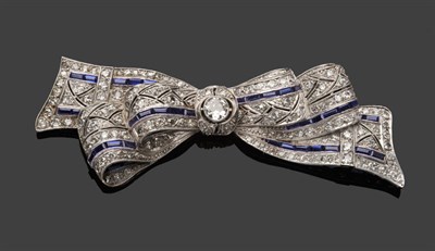 Lot 535 - A Diamond and Sapphire Bow Brooch, a round brilliant cut diamond centres the stylised bow, set...