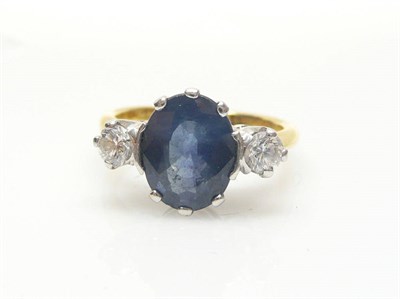 Lot 540 - An 18 Carat Gold Sapphire and Diamond Three Stone Ring, an oval mixed cut sapphire flanked by a...