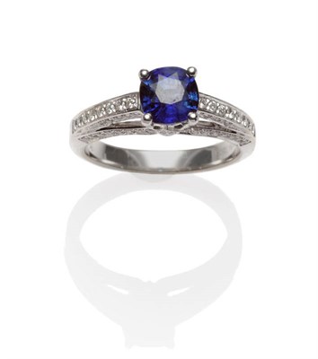 Lot 545 - A Sapphire and Diamond Ring, a round brilliant cut sapphire within bridged shoulders, diamond...