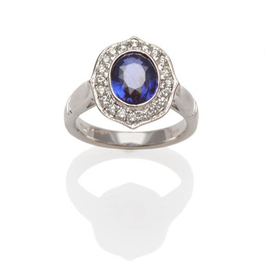 Lot 550 - An 18 Carat White Gold Sapphire and Diamond Cluster Ring, an oval cut sapphire in a bezel...