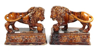 Lot 129 - A pair of 19th century treacle glazed lions on plinth bases