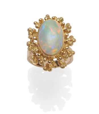 Lot 583 - An Opal Ring, the oval cabochon opal bezel set within an asymmetric beaded frame of polished...