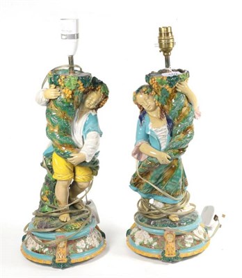 Lot 152 - A pair of late 19th century Majolica figural lamp bases, modelled on Bacchic boy and girl...